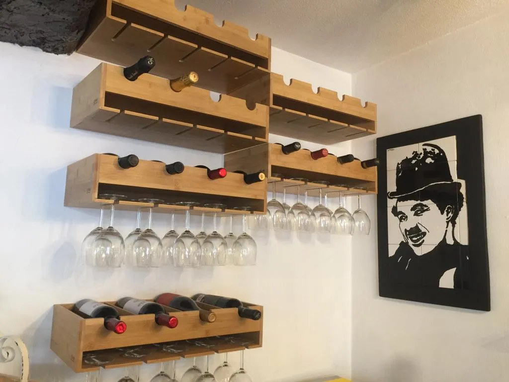 A garrafeira de bambu com os copos pendurados e o retrato do Charlie Chaplin em azulejo